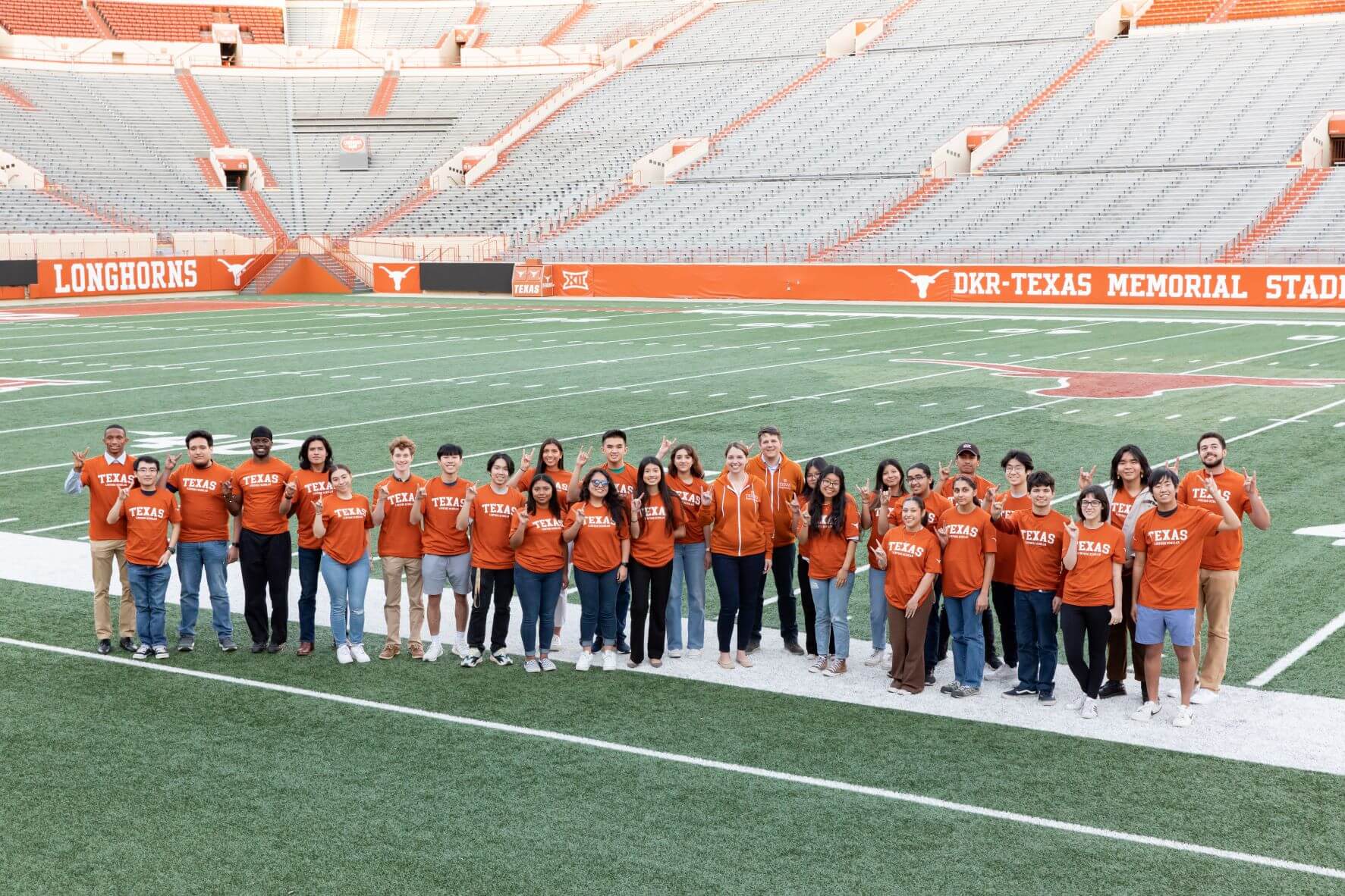 Group of UT Austin Tx engineering students standing in the football field wearing UT Austin t-shirts