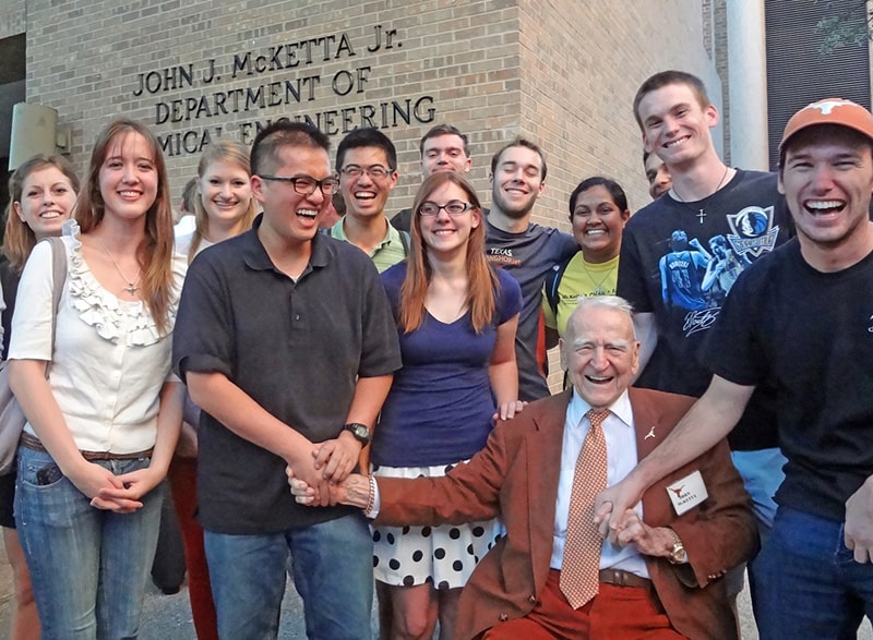 John J. McKetta wearing an orange suit and smiling with UT Texas engineering students
