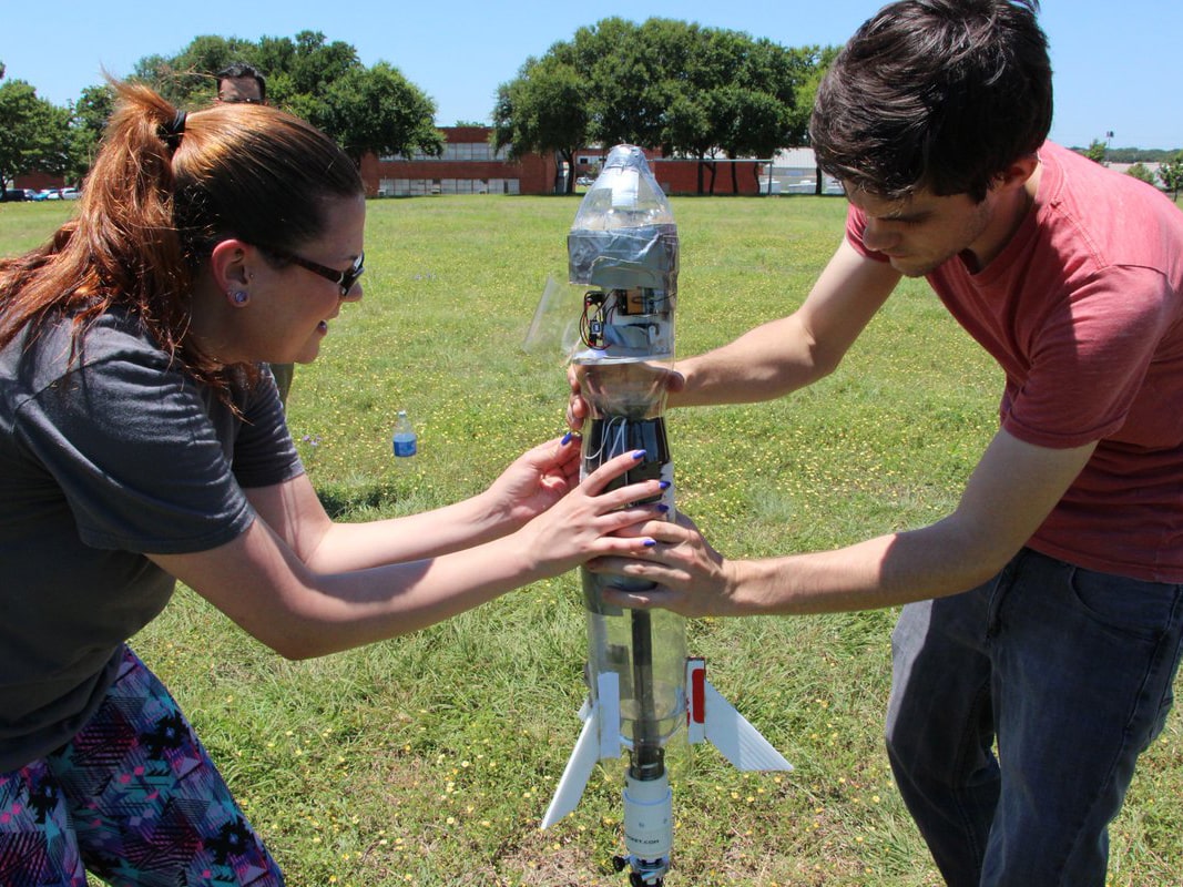 Two Texas engineering students holding model rocket