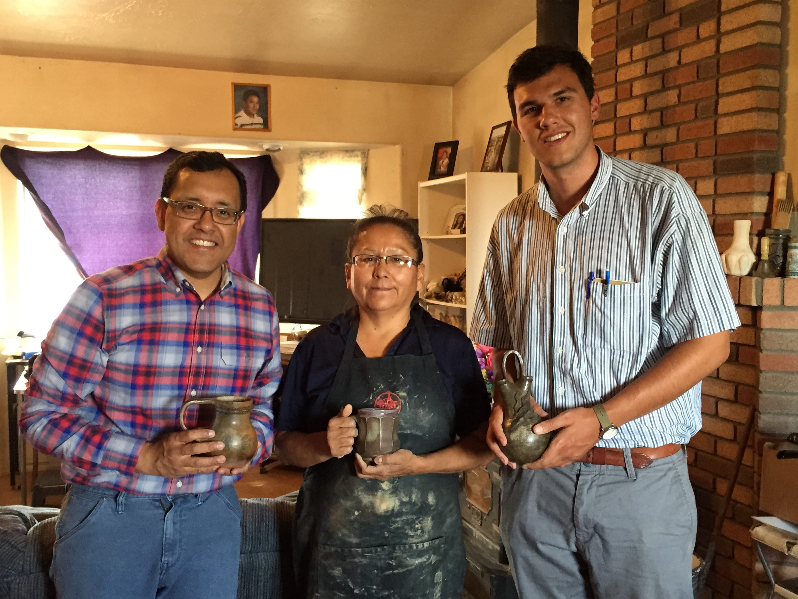 Navid Saleh, Deanna Tso and Stetson Rowles smiling while holding Navajo pottery