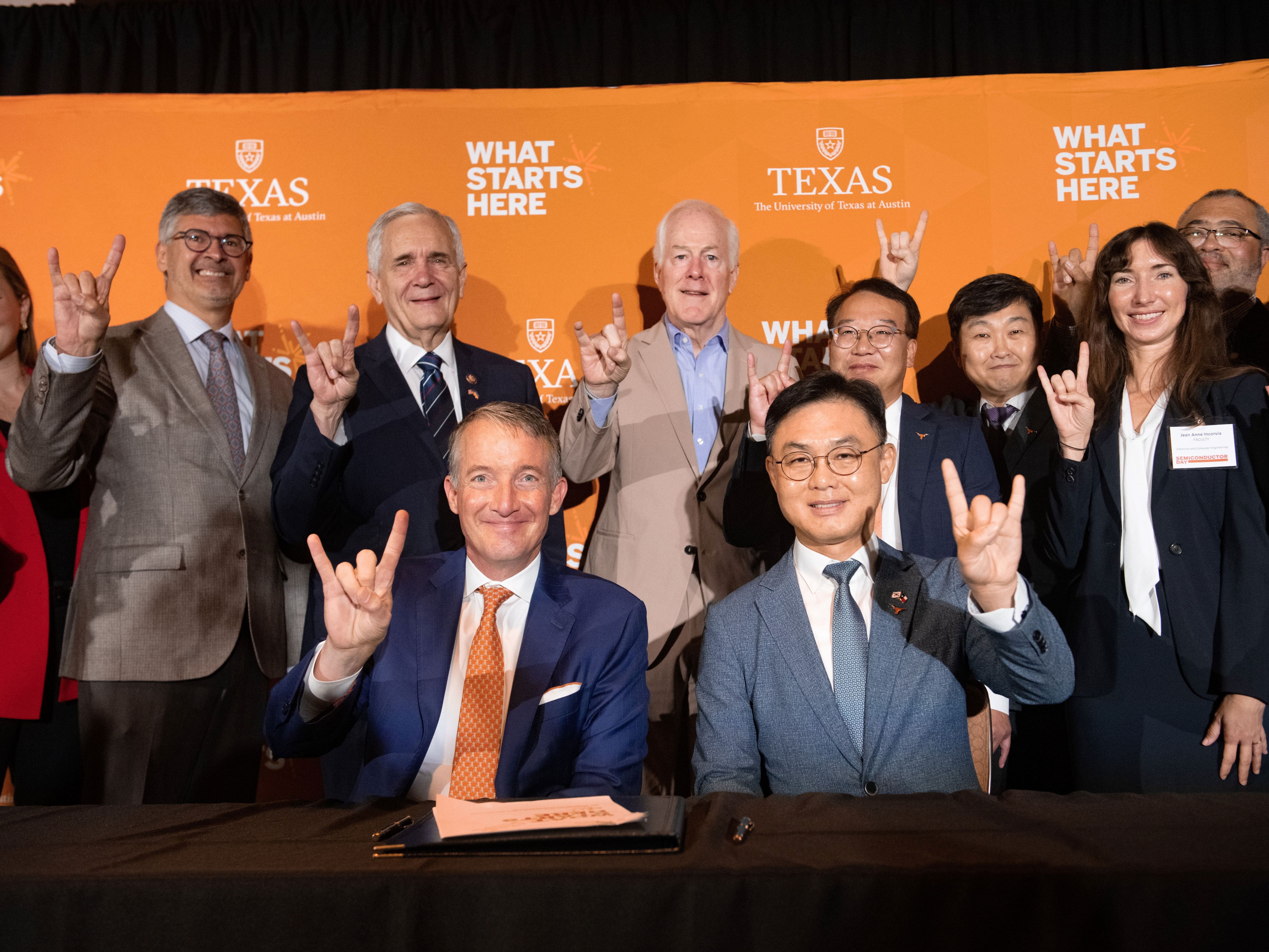 Jay Hartzell, Roger Bonnecaze and Semiconductor Day attendees doing hook 'em horns hand sign