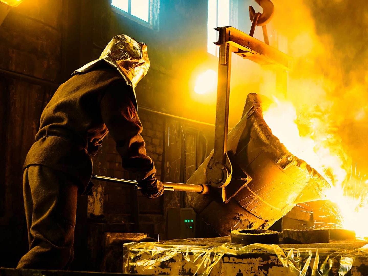 steelworker pouring molten steel into mold