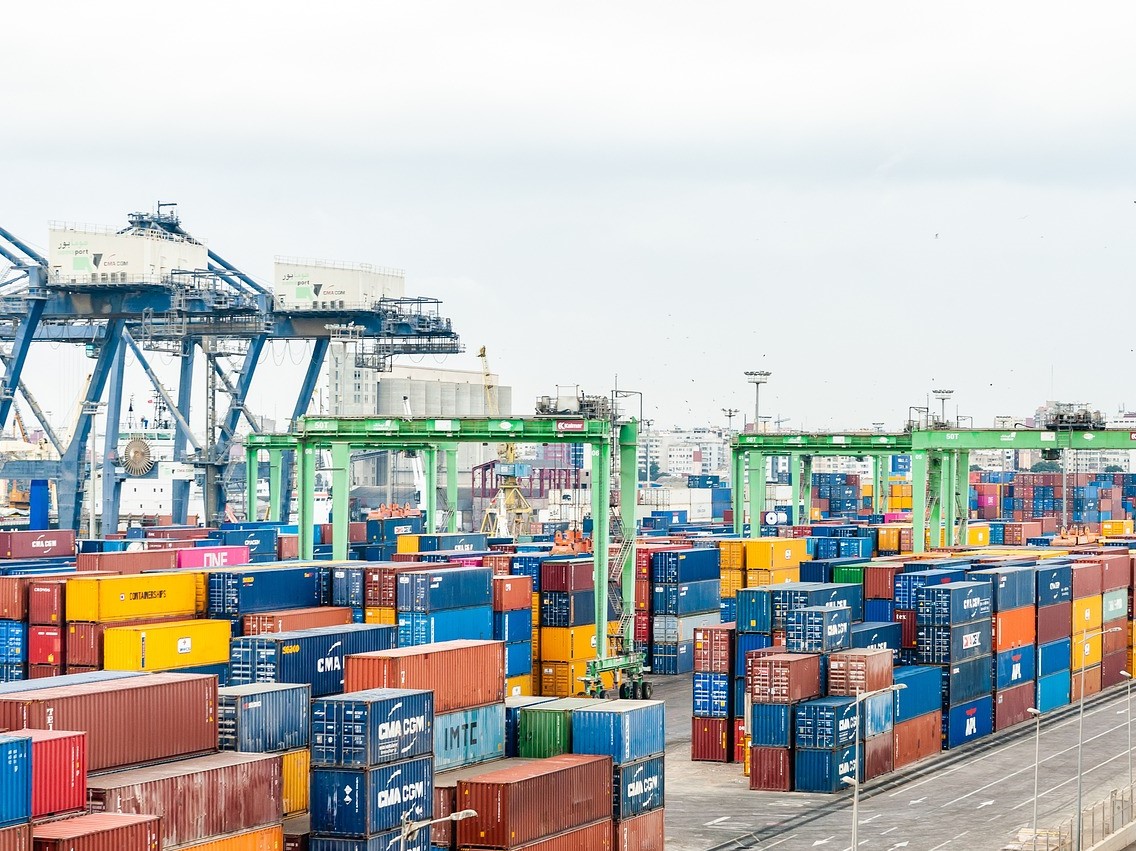 A shipping port with stacks of multi-colored shipping containers and heavy equipment