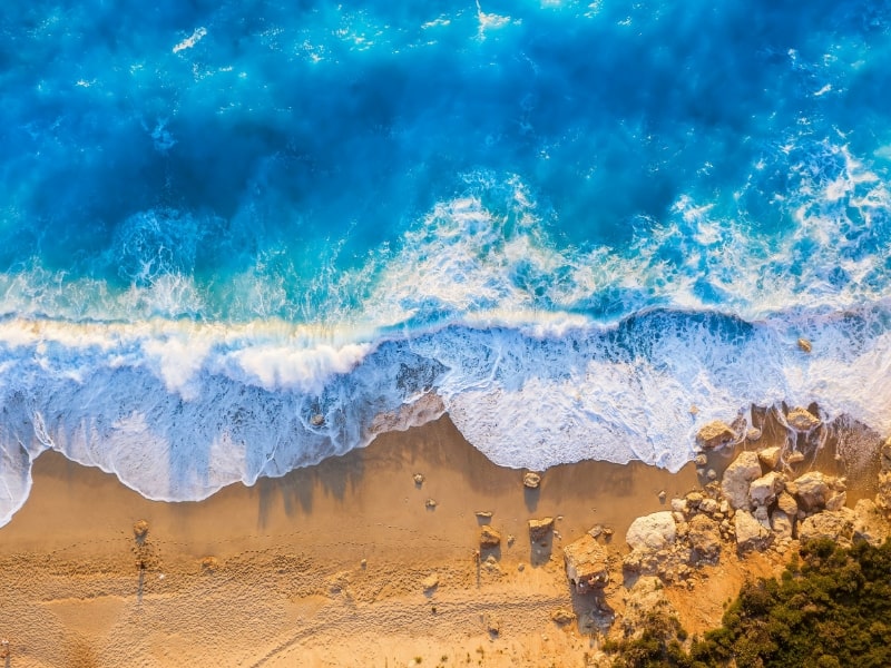 aerial view of ocean wave washing up on a beach
