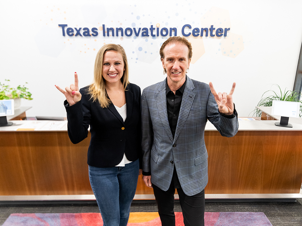 Taylor Craig and Stuart Lodge smiling with hook 'em horns hand signs in the Innovation Center