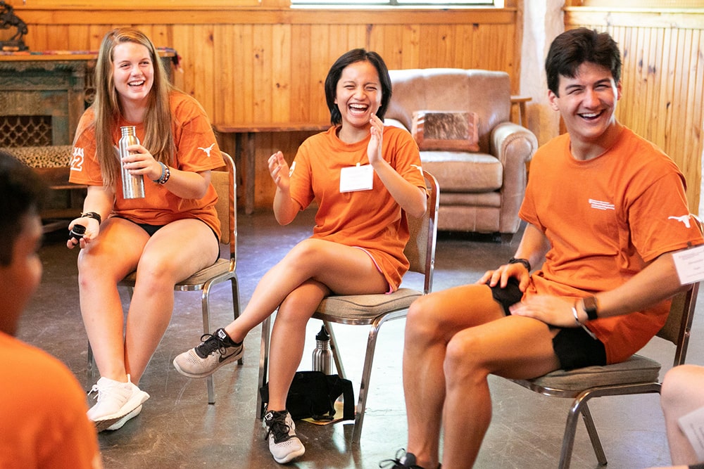 Laughing Texas Engineering students wearing UT Austin t-shirts sitting in a circle