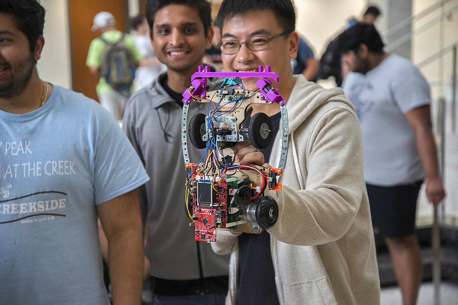 Three smiling Texas electrical and computer engineering students holding robot