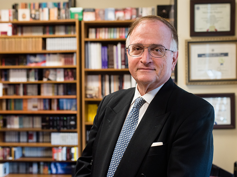 Nicholas Peppas in his office in front of a book shelf filled with CDs and records.