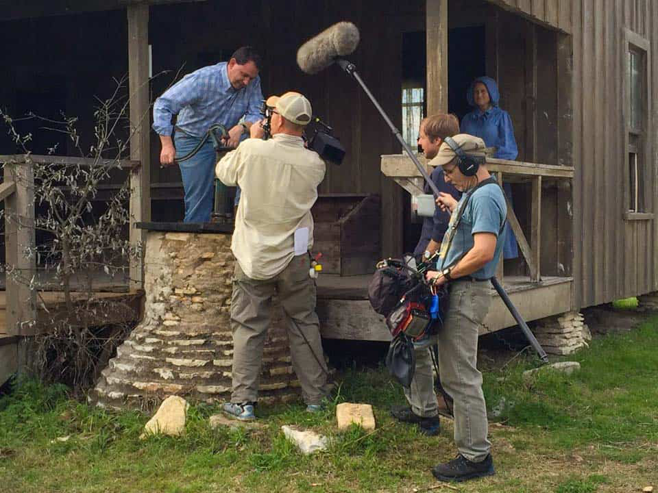 A film crew films Michael Webber pumping a water well for his PBS series.