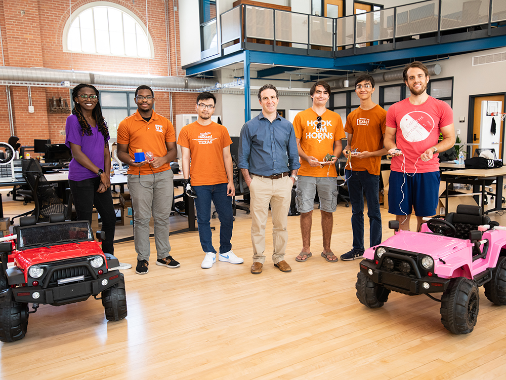 Texas Engineers smiling in front of remote control cars