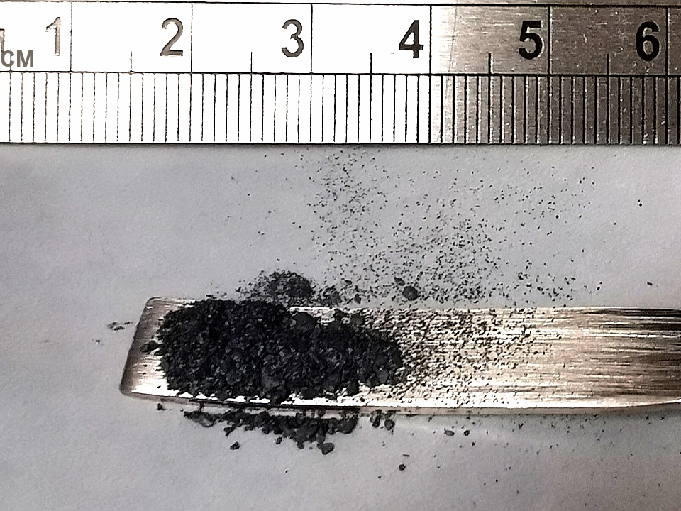 a three-inch sample of molybdenum disulfide in a spoon