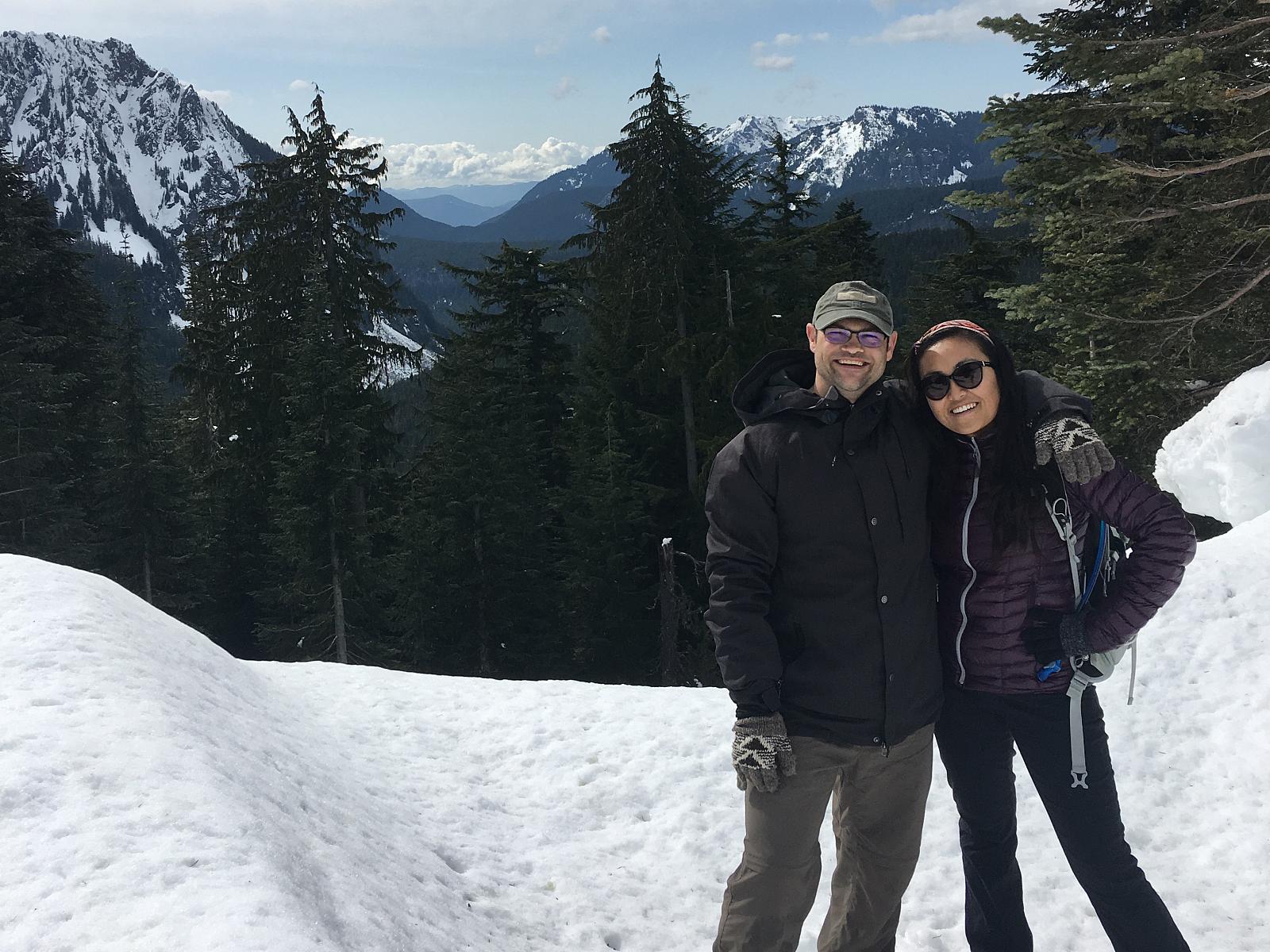 Peter with his arm around Ru in a picture of them on a snowy mountain top during a trip.